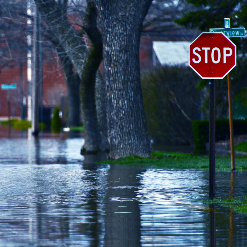A flooded intersection with a stop sign in a neighborhood.